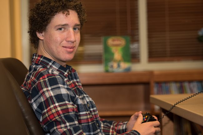 teen boy holding video game controller.