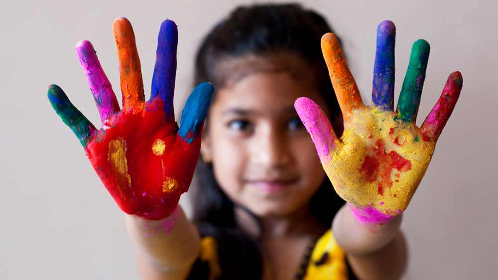 girl with outstretched hands with paint on her fingers and palms