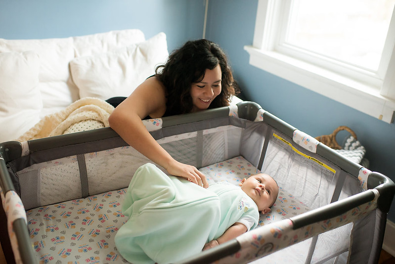 latina mother watching her baby in the crib.