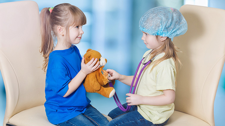 two girls playing doctor with a teddy bear