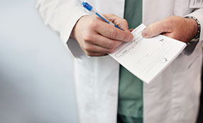 Doctor's hands writing on a prescription pad