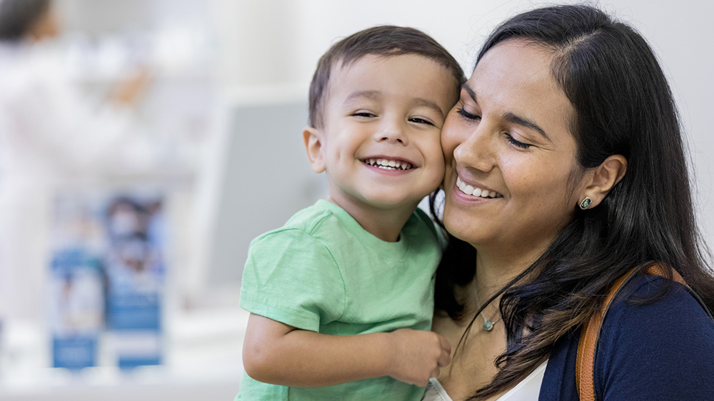 niño sonriente sostenido por su madre