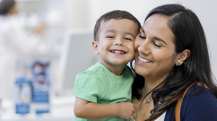 niño sonriente sostenido por su madre