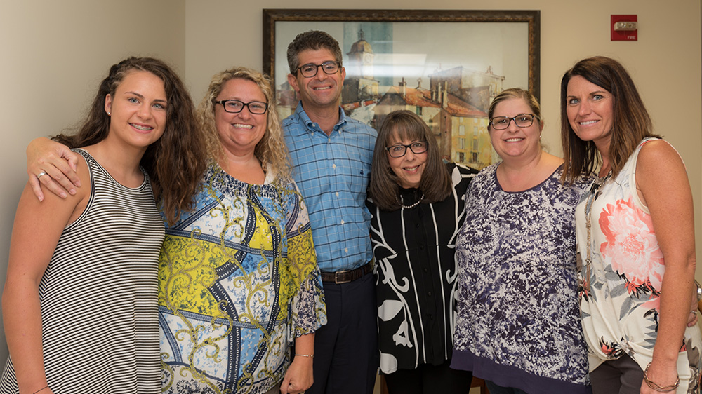 group of parents, patients and doctor perlyn smiling and hugging.