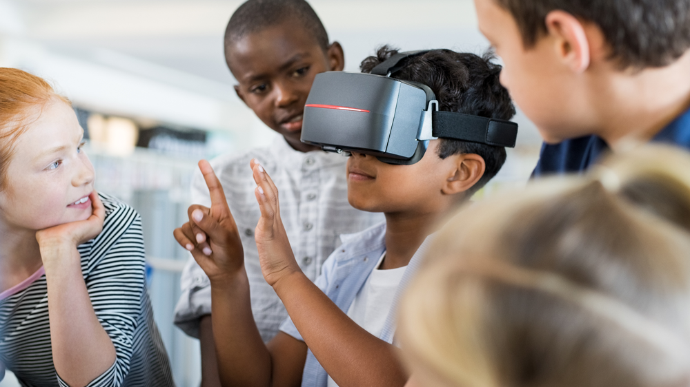 grupo de niños rodeando un niño usando un dispositivo de realidad virtual