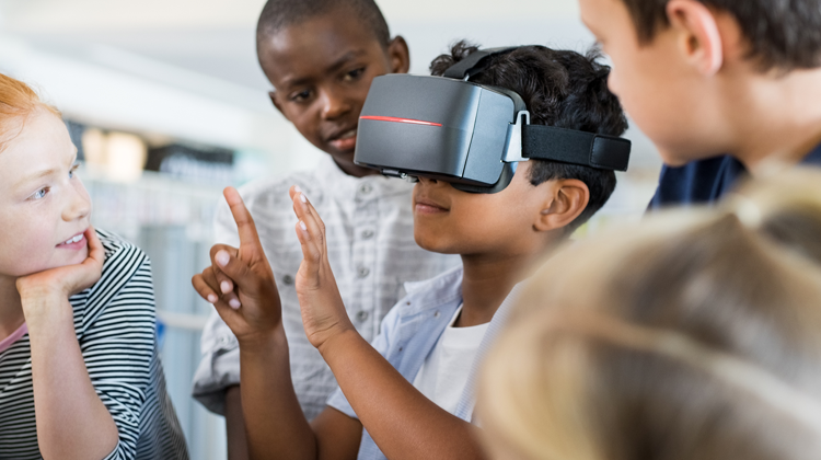 grupo de niños rodeando un niño usando un dispositivo de realidad virtual