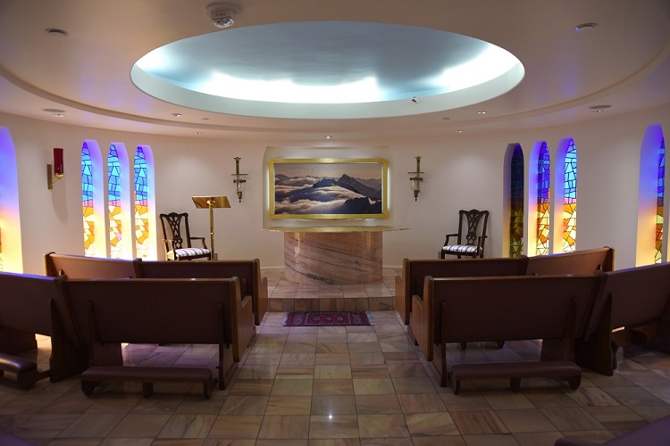 small chapel with altar, stained glass windows and pews.