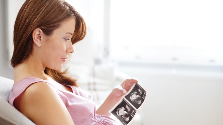 mujer embarazada observando una imagen ultrasonido del feto.