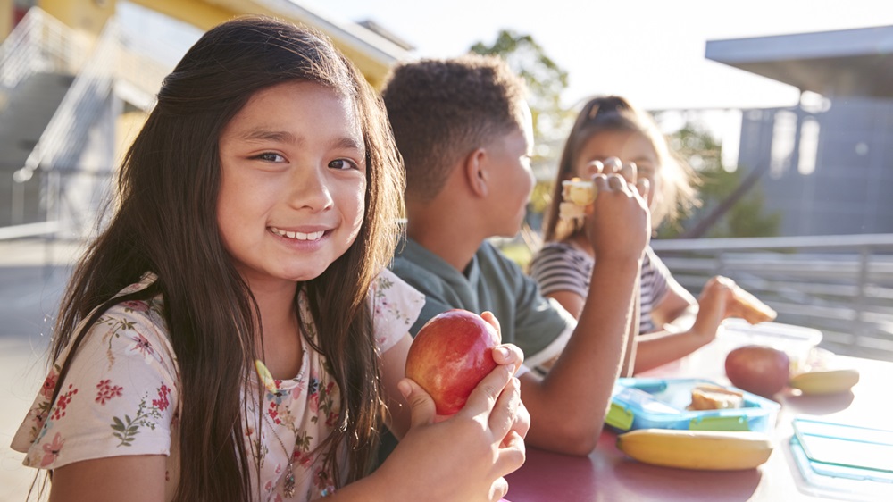 Three children at lunch table eating 