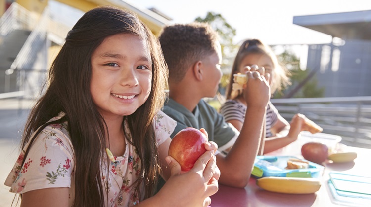 Three children at lunch table eating 