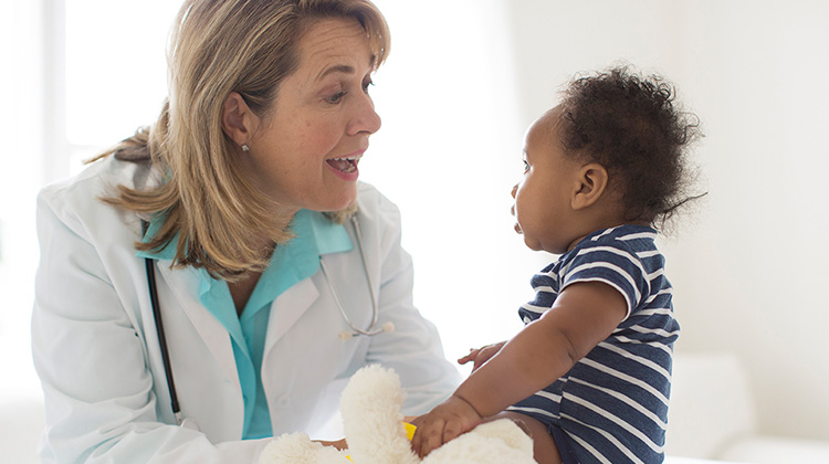 female doctor smiling at seated baby
