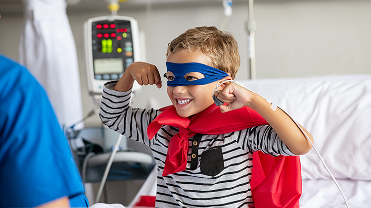 Niño fuerte en cama de hospital vestido de superhéroe