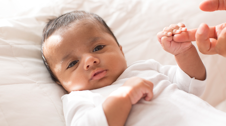 infant clasping the index finger of parent.