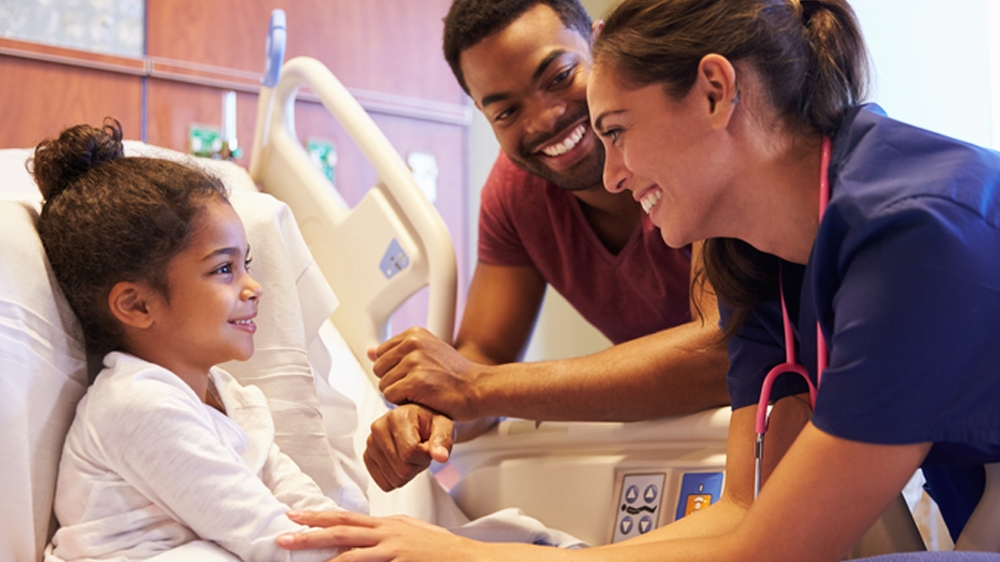 hospitalized girl and her dad smile at helpful nurse.