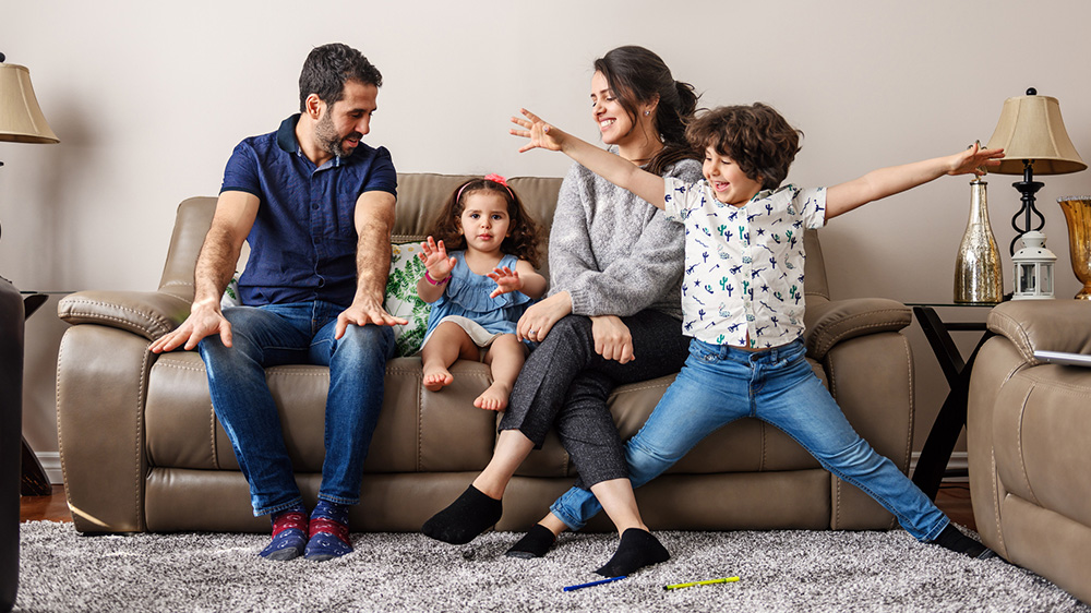 Una familia de cuatro personas divirtiéndose en su sala.