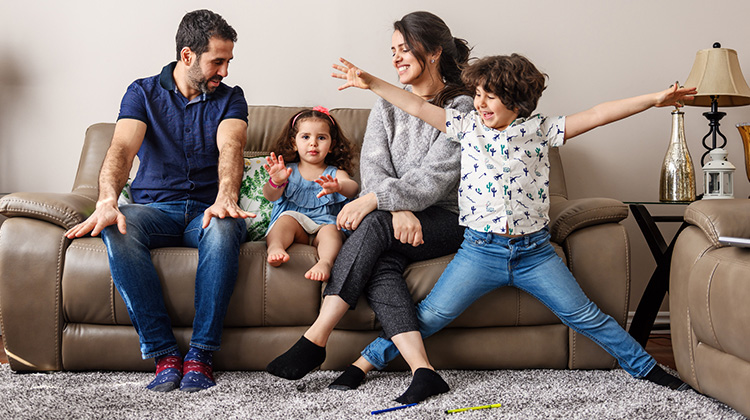 Una familia de cuatro personas divirtiéndose en su sala.