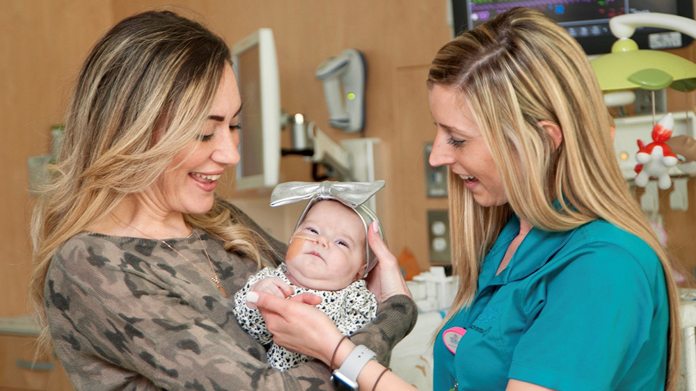 especialista de vida infantil con una madre sosteniendo su hija bebé.