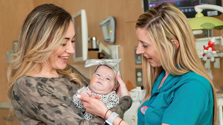 especialista de vida infantil con una madre sosteniendo su hija bebé.