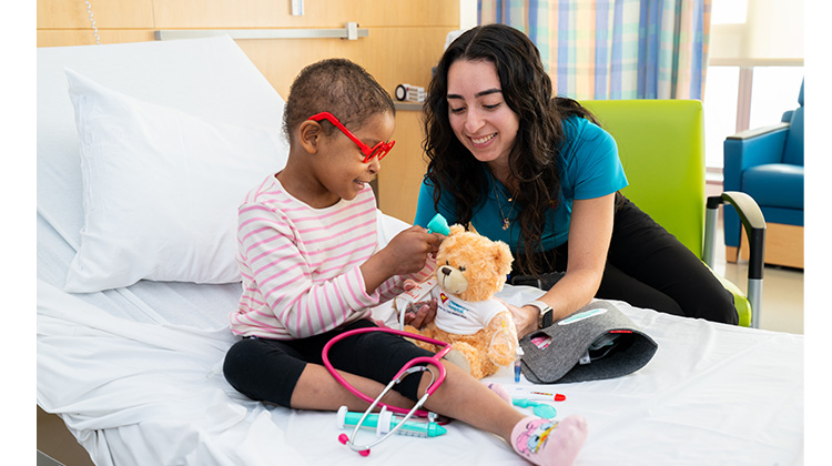 Child Life specialist teaching and playing with hospitalized girl.