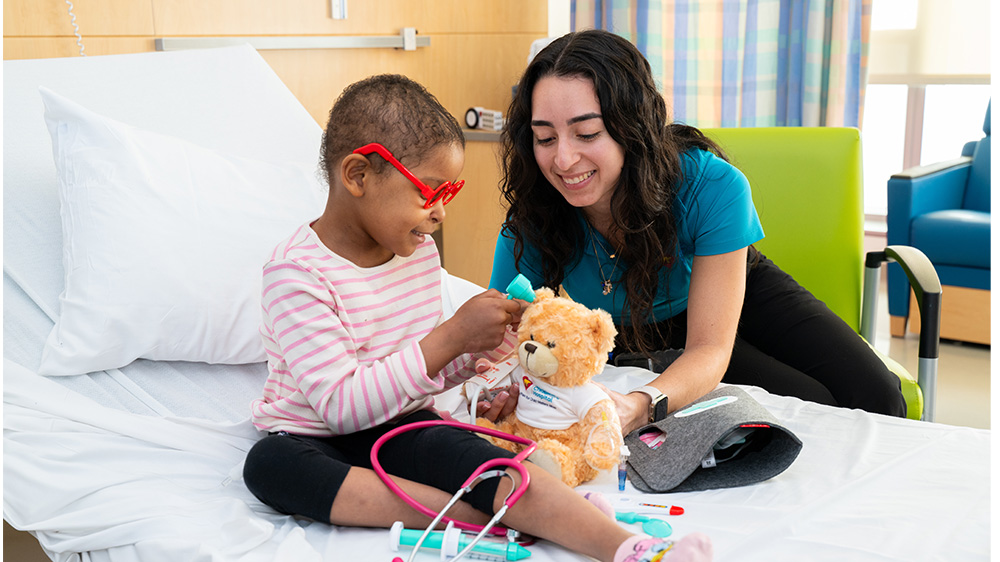 Child Life specialist teaching and playing with hospitalized girl.