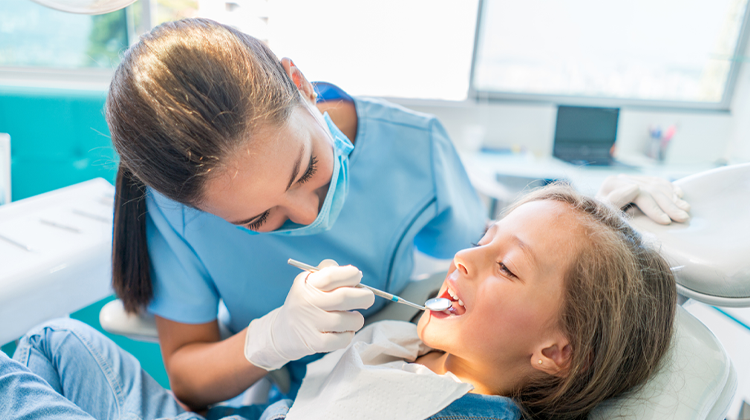female dentist tech performing a dental exam on girl.