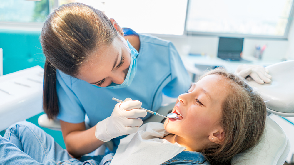 female dentist tech performing a dental exam on girl.