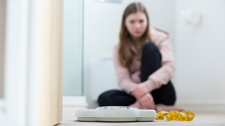 teenage girl wearily looking at a scale