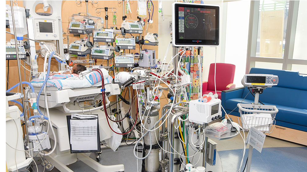 patient room with the numerous pumps, monitors, and wires of the ECMO machine.