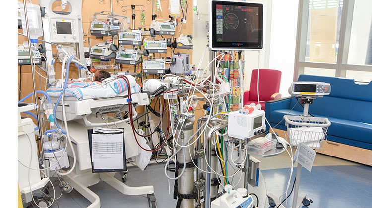 patient room with the numerous pumps, monitors, and wires of the ECMO machine.