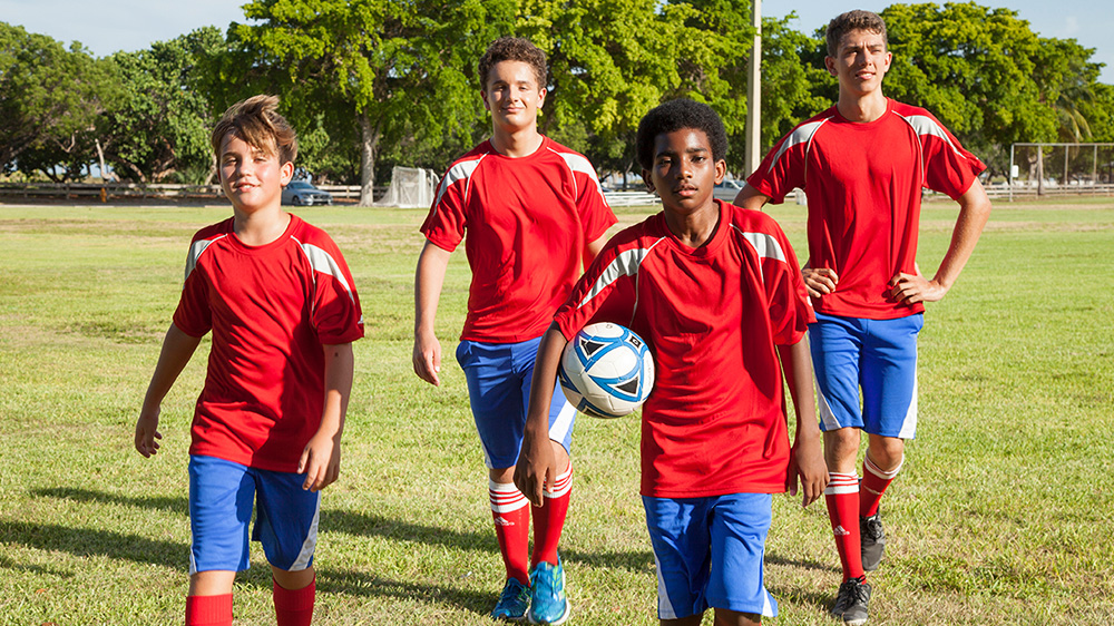 group of middle schooled boys on a soccer field.