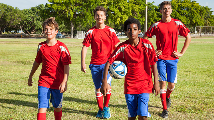 group of middle schooled boys on a soccer field.