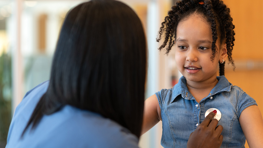 african american girl having her heart checked by a nurse.