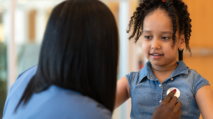 enfermera examina el corazón de una niña afro americana