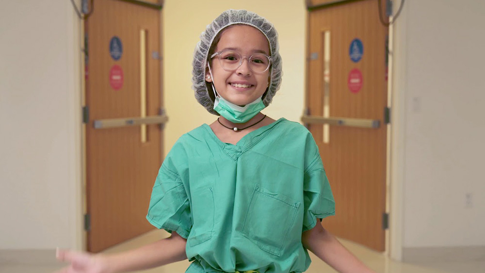 Paciente recuperada, maja, con bata quirúrgica mientras recorre el hospital