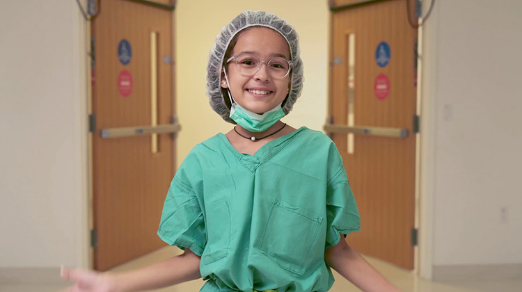 Paciente recuperada, maja, con bata quirúrgica mientras recorre el hospital