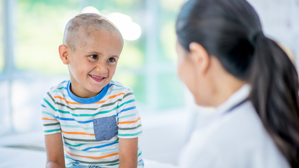 boy with shaved head smiling at doctor