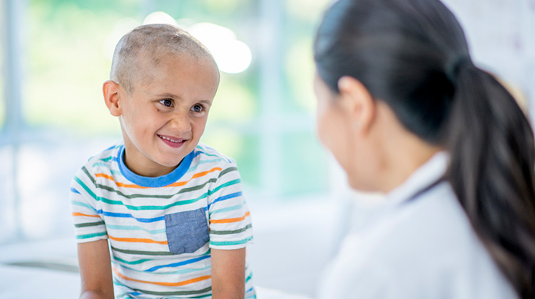boy with shaved head smiling at doctor