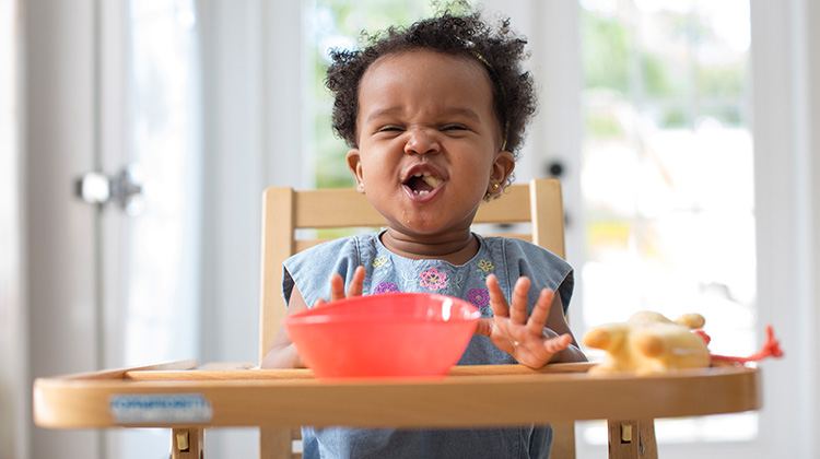 toddler girl eating on a high chair