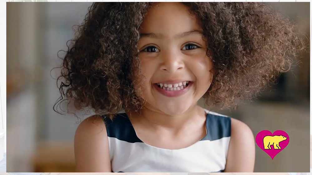 smiling girl with curly hair. click to watch video.