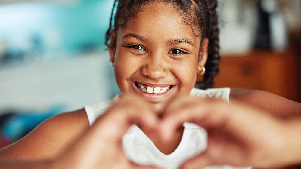 girl making a heart shape with her hands