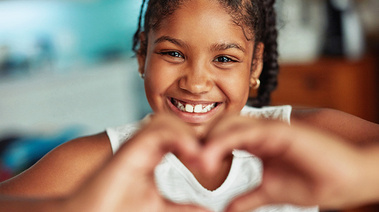 niña formando un corazón con las manos