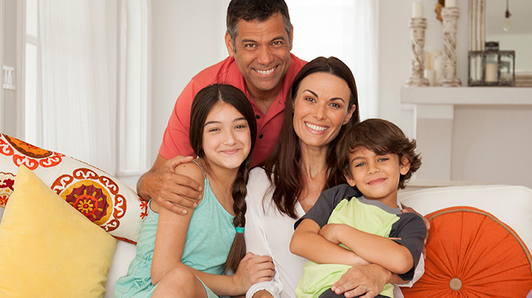 family of four hugging on their home couch.