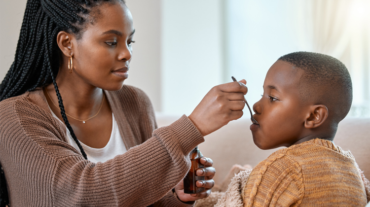 mother giving medicine to her son with a spoon