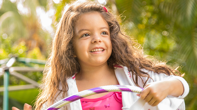 girl with caramel colored hair smiling in the sunlight.