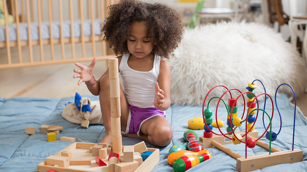 curly haired girl playing with wood blocks