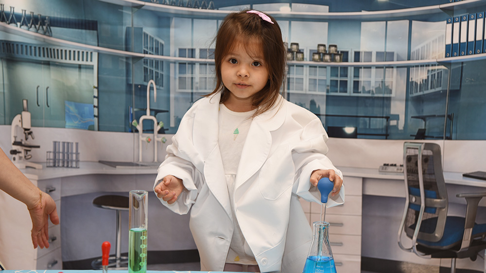 cute girl in an oversized lab coat playing with test tubes.