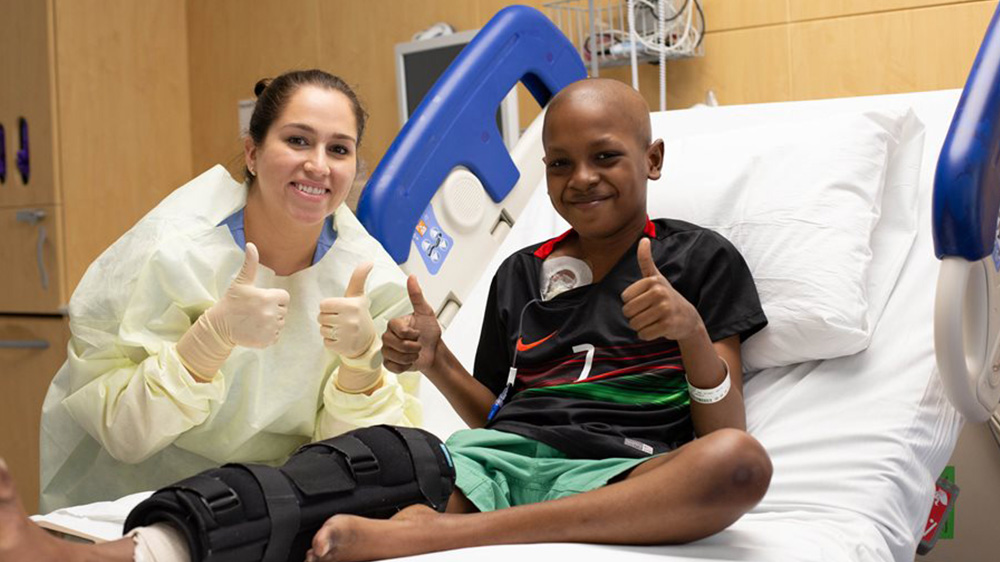 former patient Tyler with his nurse, giving the thumbs up after surgery