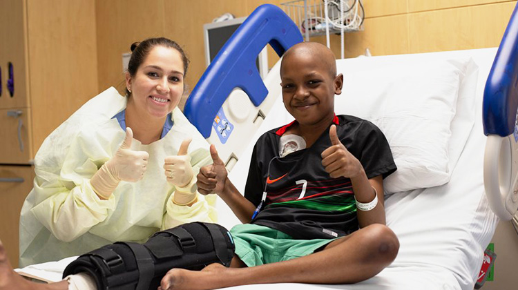 former patient Tyler with his nurse, giving the thumbs up after surgery