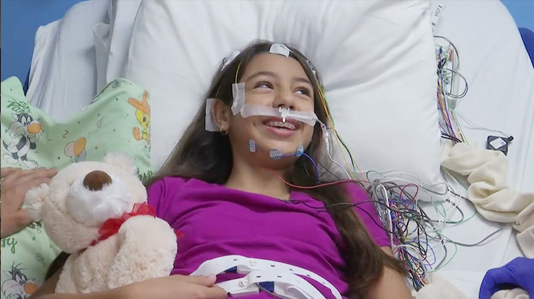 Girl with long hair in bed with electrodes on her forehead ready for her sleep study.