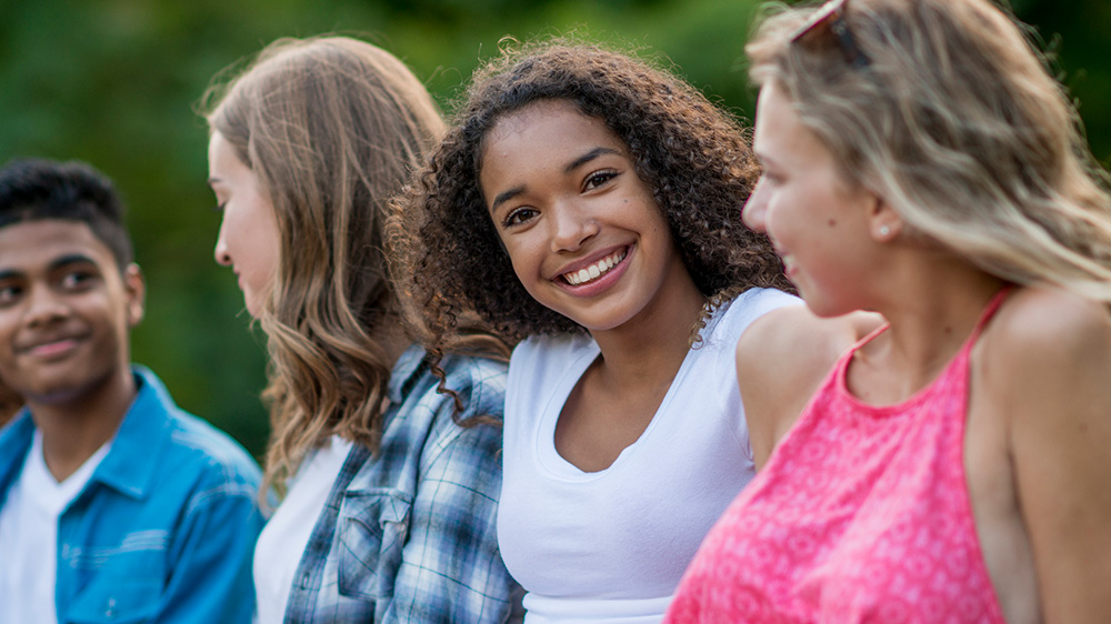 teenage girl smiling while sitting with friends
